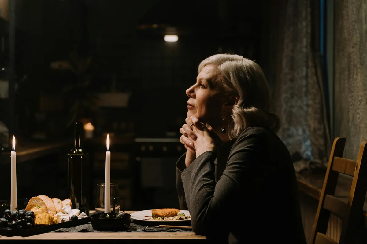 A woman reading a document at her kitchen table with a concerned expression